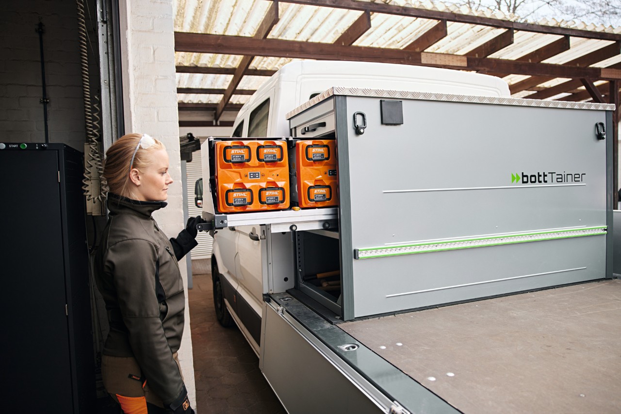 Side profile of a blonde woman next to a flatbed vehicle handling batteries in the bottTainer