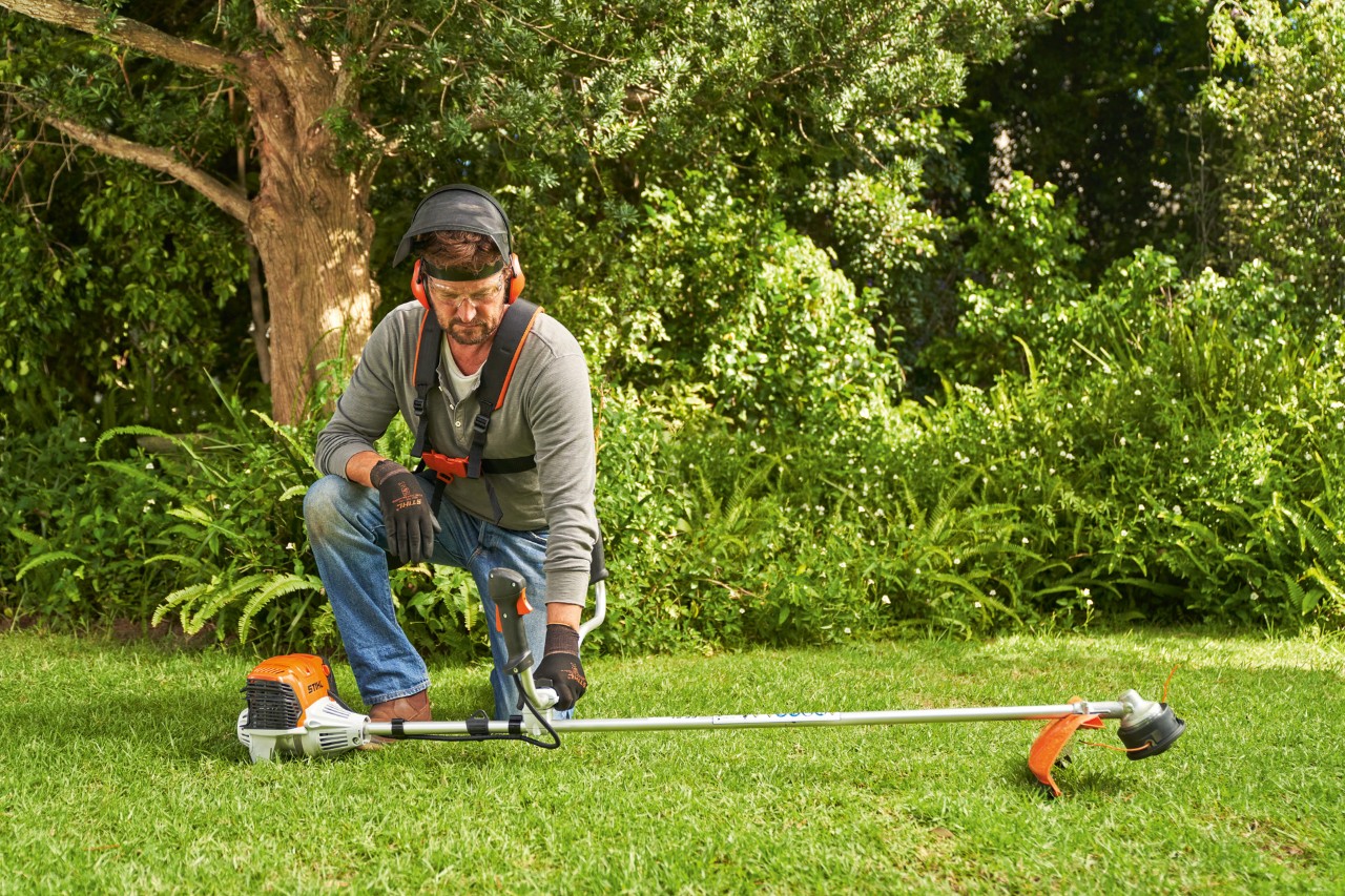 A man placing a STIHL FS 91 petrol brushcutter on the ground to start it