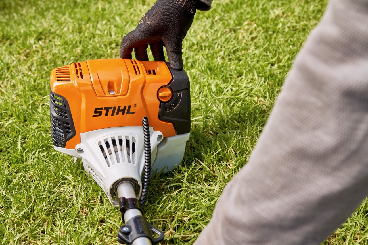 A man pressing a STIHL FS 91 petrol brushcutter firmly onto the ground