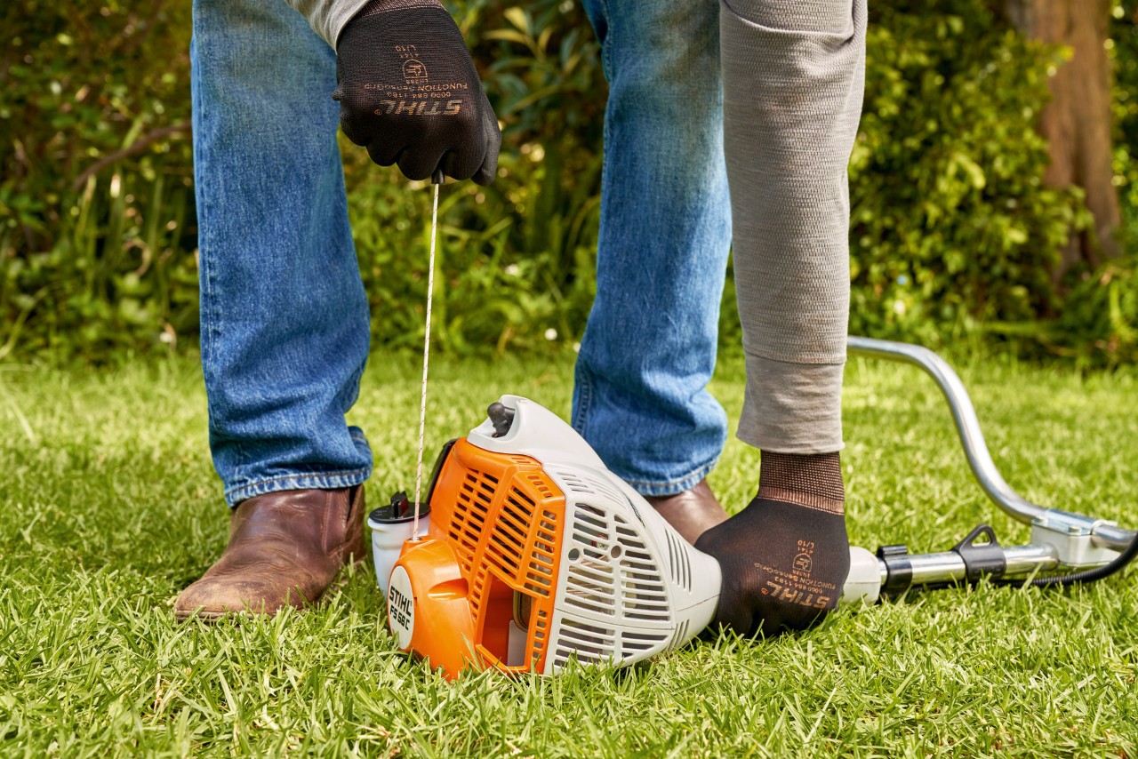 A man pulling the starter cord of a STIHL FS 56 petrol brushcutter 