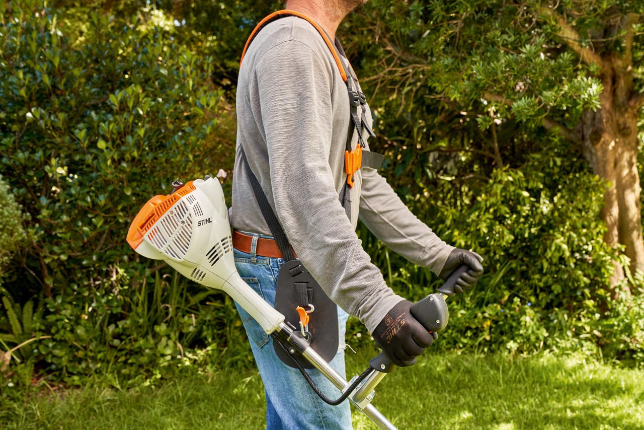 A man raising a STIHL FS 56 petrol brushcutter from the ground